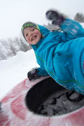 A happy boy on a snow tube. 