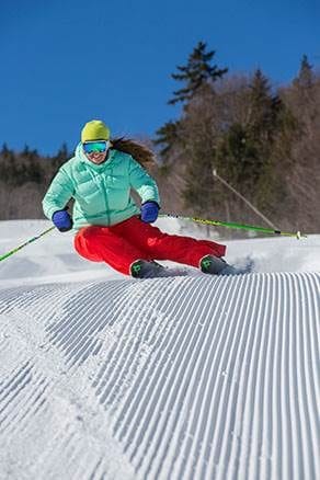 A woman skiing corduroy on a clear blue day. 