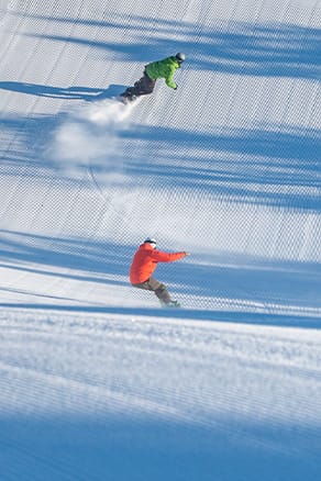 Two Snowboarders chase each other down fresh cord at Sunday River