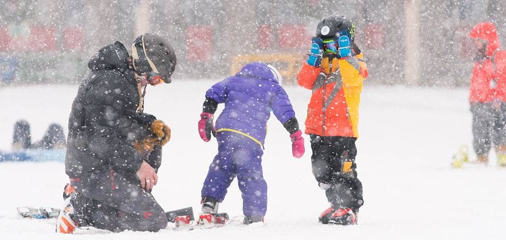 Kids putting on skis in snow