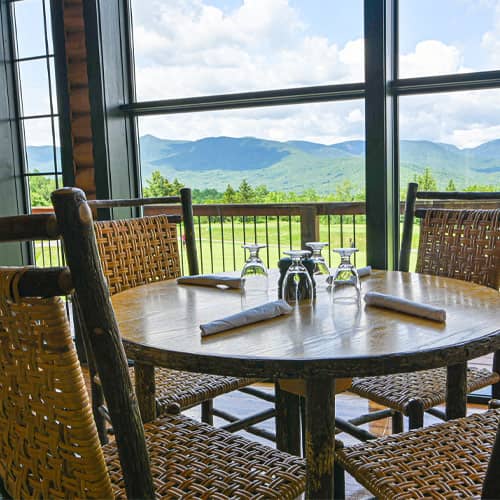 A set table next to the floor to ceiling windows inside of the Clubhouse at Sunday River  