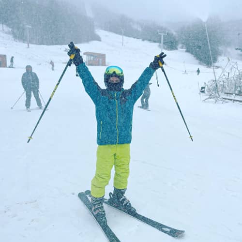 Excited skier, arms up snowing
