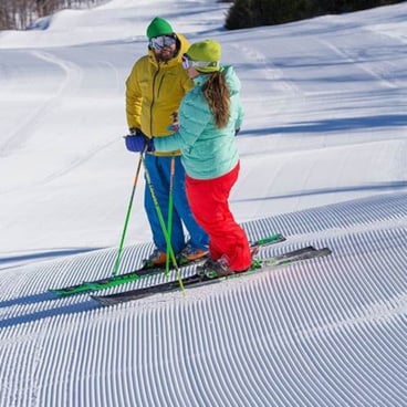 Skiers on groomed snow in bright clothes